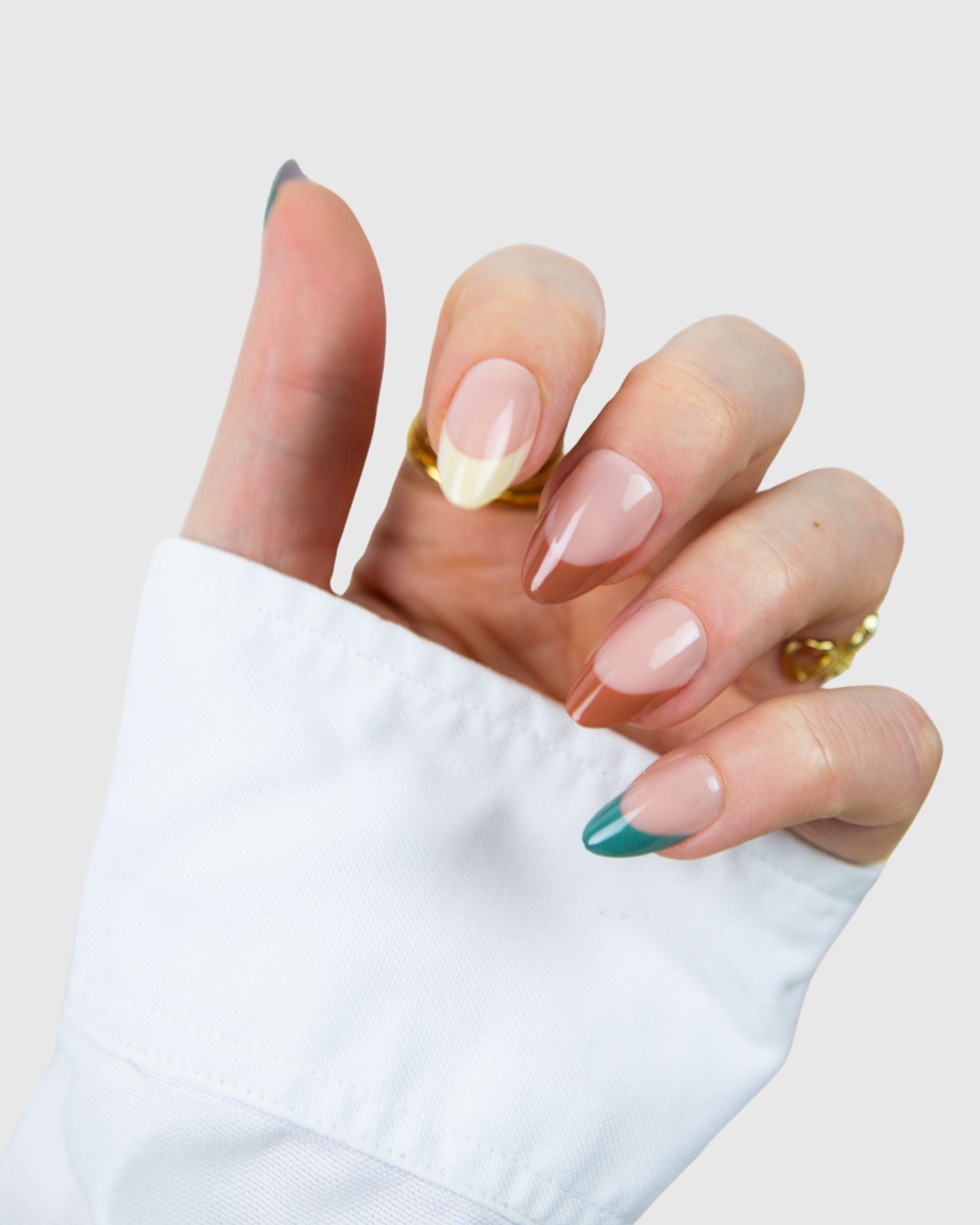 A hand wearing a set of Loste press-on nails in a multi-colour French design