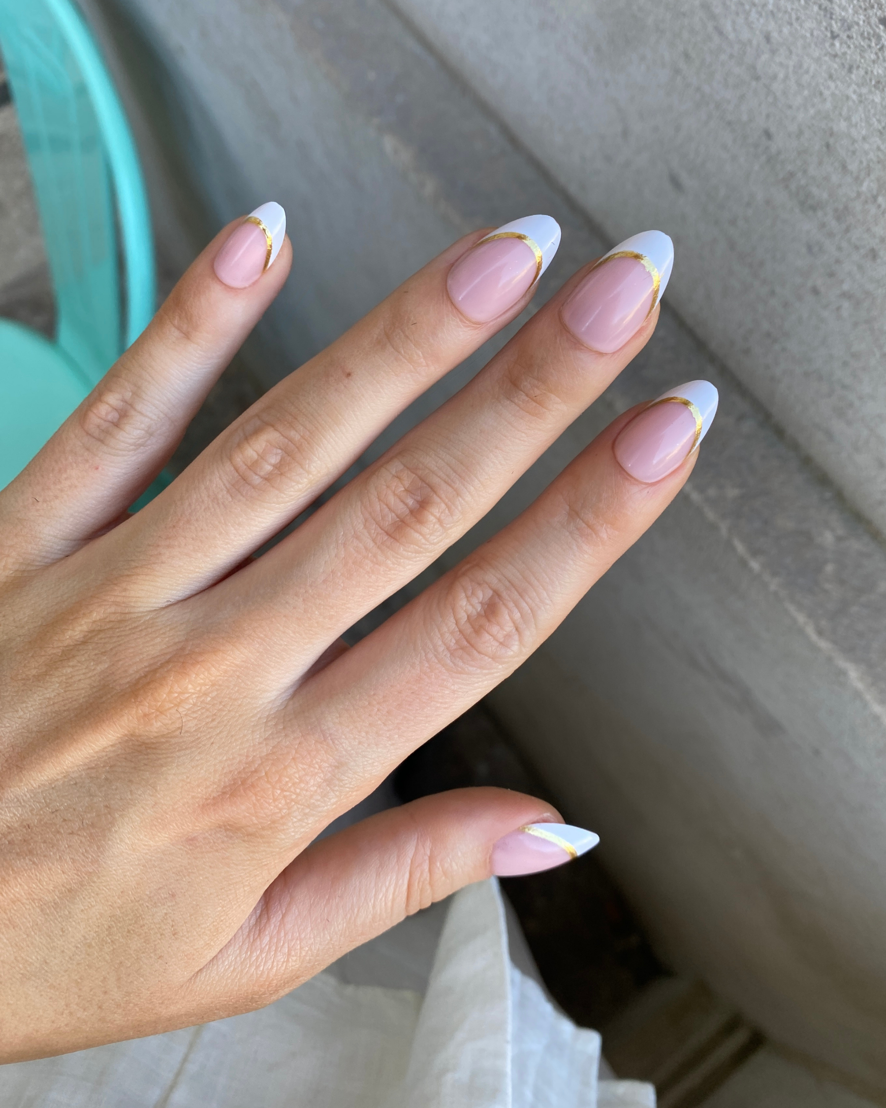 A hand holding a box of Loste press-on nails with a white and gold French tip design
