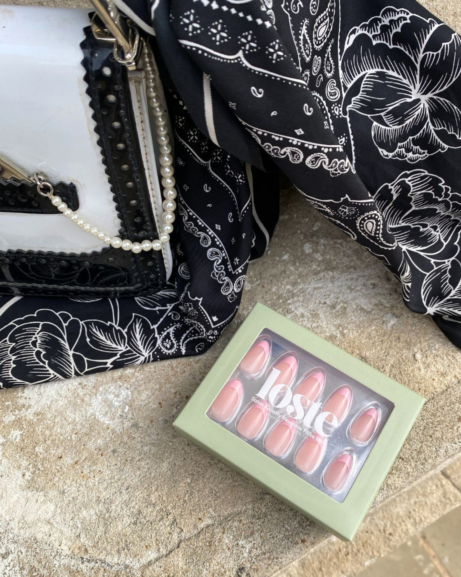 A flatlay style image showing a handbag next to a box of Loste press on nails