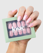A hand holding a box of Loste press-on nails in a pink cat-eye design